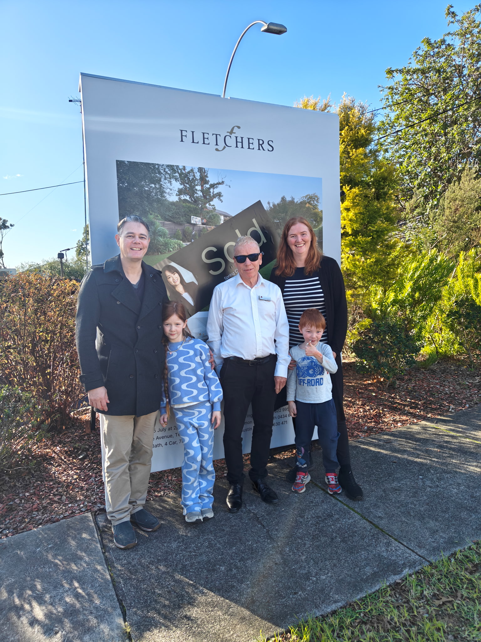 Mark Thompson of MPS Advocates with a Melbourne family beside a sold property board after a successful property result
